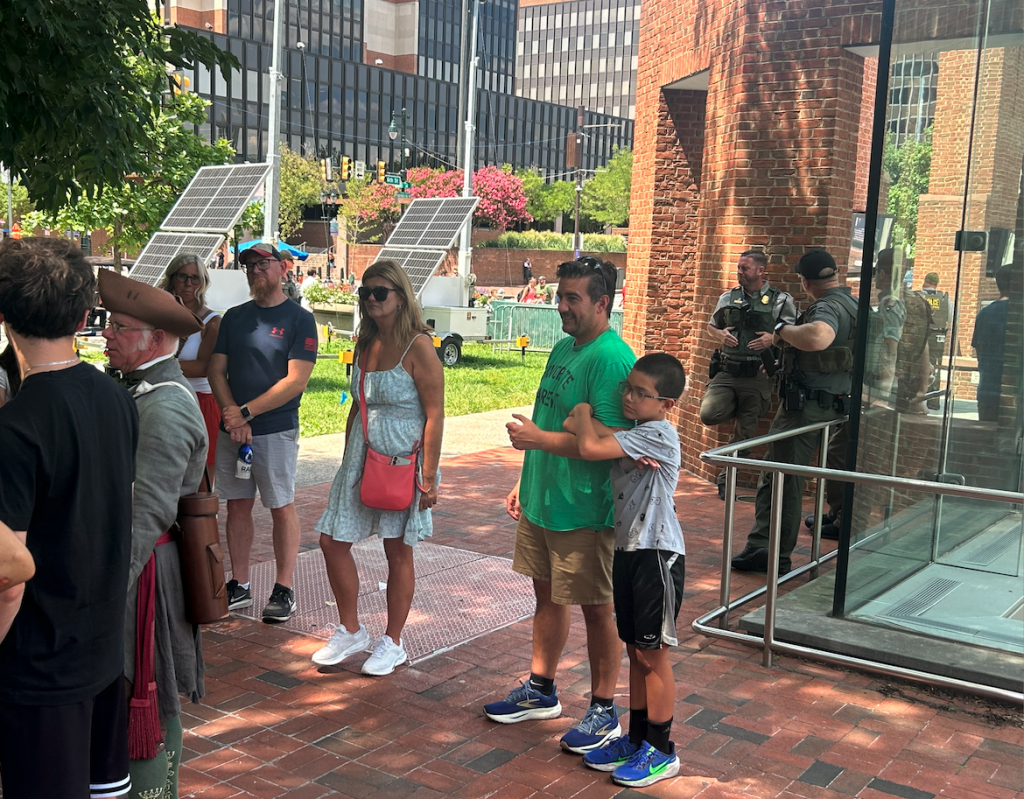 Three Fed Park Police guard President's House Exhibit in Philadelphia as tour guide in period costume holds forth to crowd
